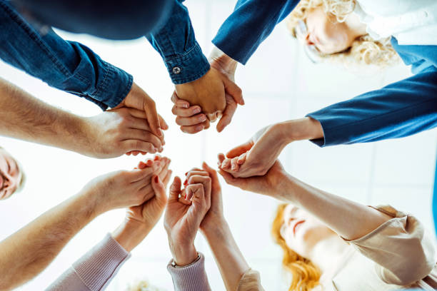 istock Diverse people in circle holding hands at group therapy 1386881722