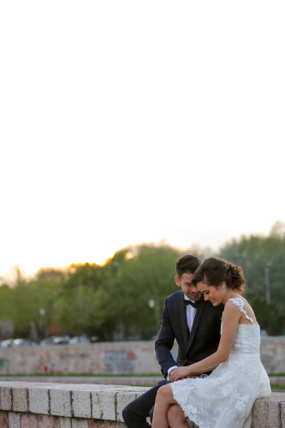 Young newlywed couple sitting on city quay on sunny day