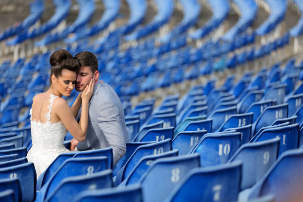Beautiful newlywed young couple sitting at the empty stadium