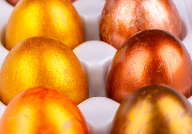 istock Close-up of Easter painted eggs in gold and bronze in a white package. 1386883277