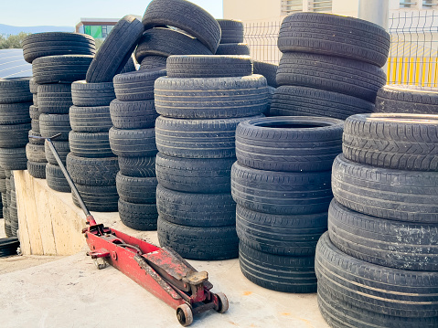 Heap of many rubber tires wall background. Old used worn car and truck wheels tires pile stacked in rows stored for recycling. Industrial pollution of environment.