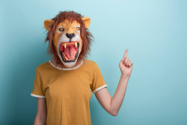 istock Woman in lion mask pointing with hand and index finger to the side blank space 1386885708