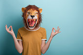 Young woman in lion mask with raised hands in meditation yoga mudra sign