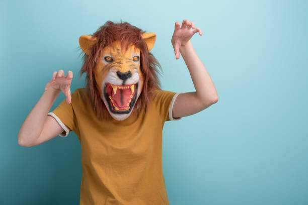 istock Young woman in lion mask making scary attack gestures with hands 1386885895