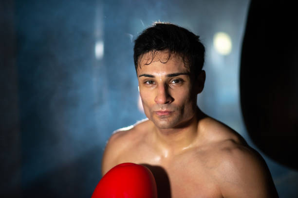 istock Brunette shirtless boxer in dark gym 1386888296