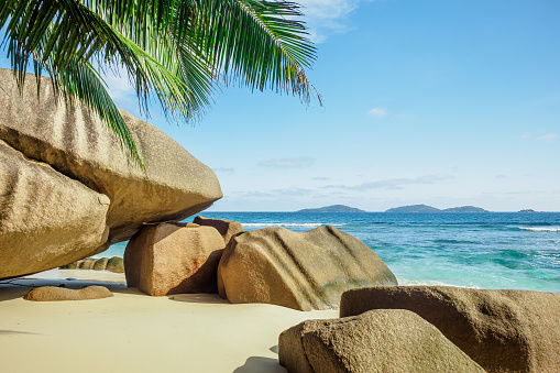 Huge granite boulders and palm trees on the shores of the Indian Ocean. Paradise beach and tropical getaway on La Digue island, Seychelles