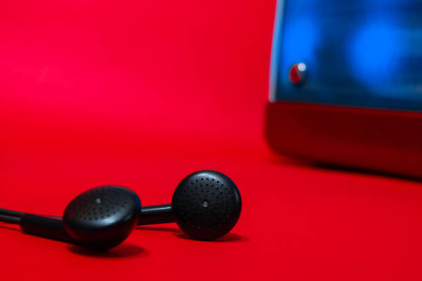some well focused black headphones on one of them with a speaker with out of focus backlight and all red background