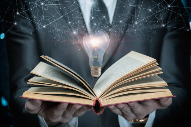 istock A man in a suit shows an open textbook and a burning light bulb . 1386890131