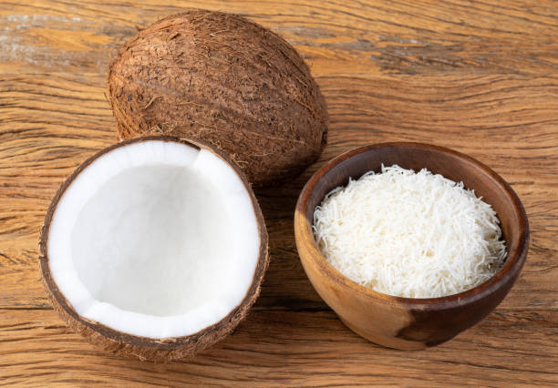 istock Grated coconut flakes in a bowl with fruit over wooden table 1386892984