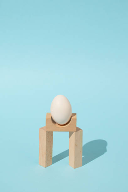 istock Trendy surrealism sunlight composition made with egg and wooden geometric elements on bright light blue background. Minimal architectural concept. 1386894438