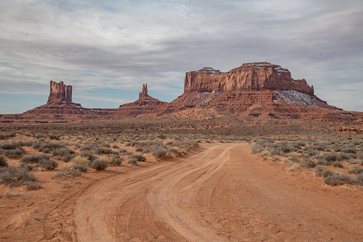 Scenic view dirt road in Monument Valley made famous by  many USA western movies of the wildwest. In the background are famous sandstone formations in northeast Arizona in the United States of America (USA). John Morrison Photographer