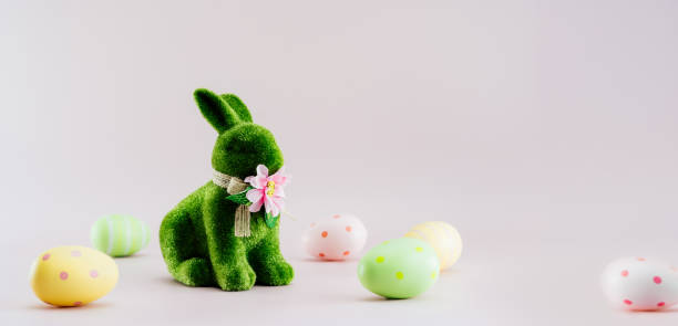 ニュートラルピンクの背景に異なるパターンで緑色のウサギウサギの置物と色のイースターエッグ。お祝いのエステルスプリングカードモックアップ。ワイドバナー。選択的な焦点。スペー� - easter egg figurine easter holiday ストックフォトと画像