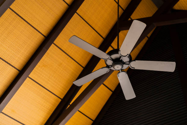 brown indoor ceiling fan on an exposed wooden support beam, with a decorate wooden ceiling, in the hall of living room of a contemporary home interior,home interior design concept brown indoor ceiling fan on an exposed wooden support beam, with a decorate wooden ceiling, in the hall of living room of a contemporary home interior,home interior design concept ceiling fan stock pictures, royalty-free photos & images