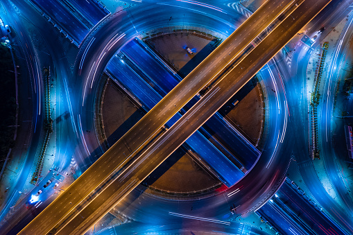 Aerial view of car traffic transportation above circle roundabout road in Asian city. Drone aerial view fly in circle, high angle. Public transport or commuter city life concept of economic and energ