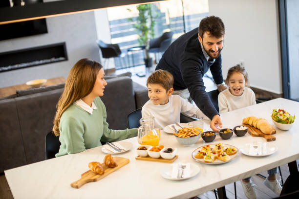istock Young happy family talking while having breakfast at dining table 1386900559