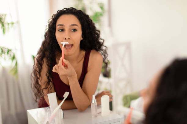 Pretty young brunette woman shaving her upper lip, removing unwanted moustache in front of mirror at home, blank space Pretty young brunette woman shaving her upper lip, removing unwanted moustache in front of mirror at home, blank space. Spa treatment, smooth skin and beauty care concept facial hair stock pictures, royalty-free photos & images