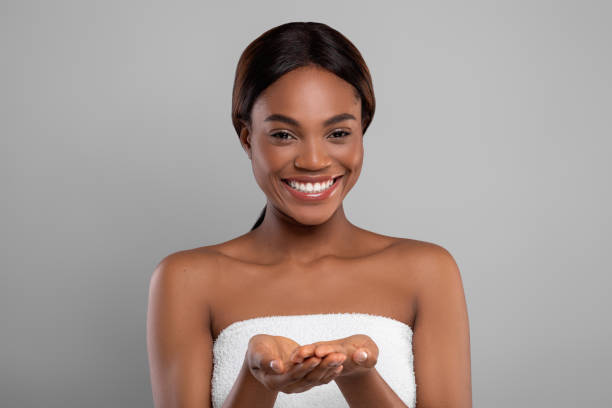 istock Happy Black Female Wrapped In Bath Towel Demonstrating Something On Empty Palms 1386902075