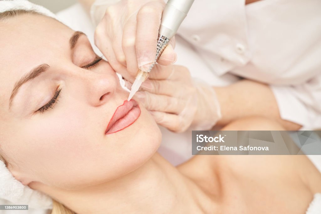 Permanent makeup. Beauty spa procedure. young woman. Face tattoo Permanent makeup. Beauty spa procedure. young woman. Face tattoo. Lip micropigmentation. Professional face microblading. Female cosmetology device. Copyspace. Mouth treatment. Dermatology Human Lips Stock Photo