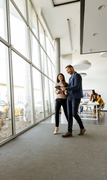 istock Young entrepreneur couple walking together and using digital tablet in the modern office 1386912551