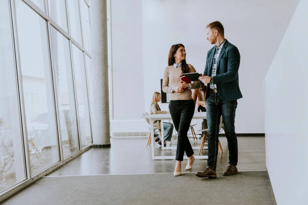 istock Young entrepreneur couple walking together and using digital tablet in the modern office 1386912565