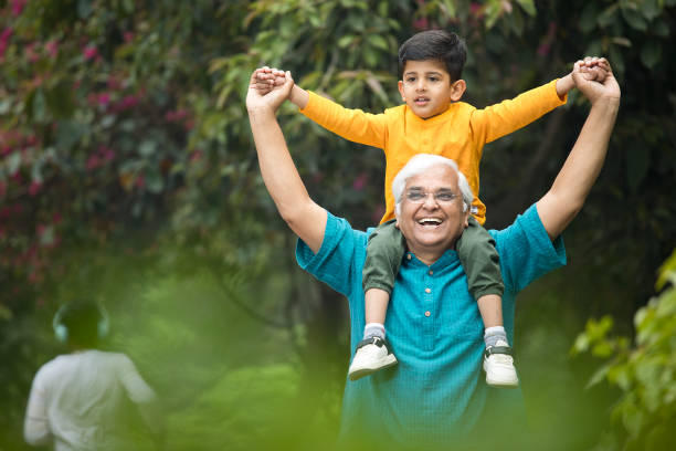 istock Old man carrying grandson on shoulders at park 1386915075