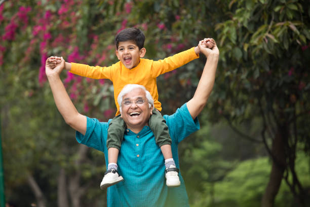 istock Old man carrying grandson on shoulders at park 1386915123