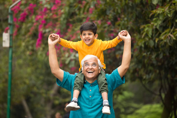 istock Old man carrying grandson on shoulders at park 1386915173