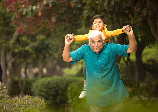 istock Old man carrying grandson on shoulders at park 1386915205