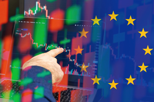 European Union downtrend of the economy in a world crisis. Man hand shows on the decreasing candle stick graph chart in the stock market with the flag on the background, March 2022, San Francisco, USA