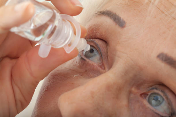 senior woman drips eye drops into her eyes - lubrication infection imagens e fotografias de stock