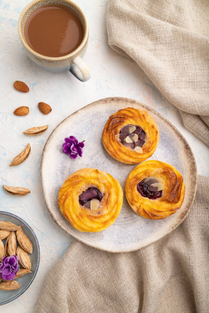 istock Small cheesecakes with jam and almonds with cup of coffee on a white concrete background. top view, close up. 1386917975