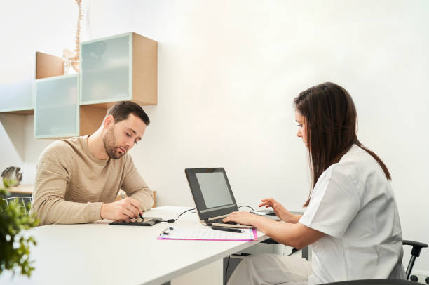 The physical therapist and the patient fill out a patient form. stock photo