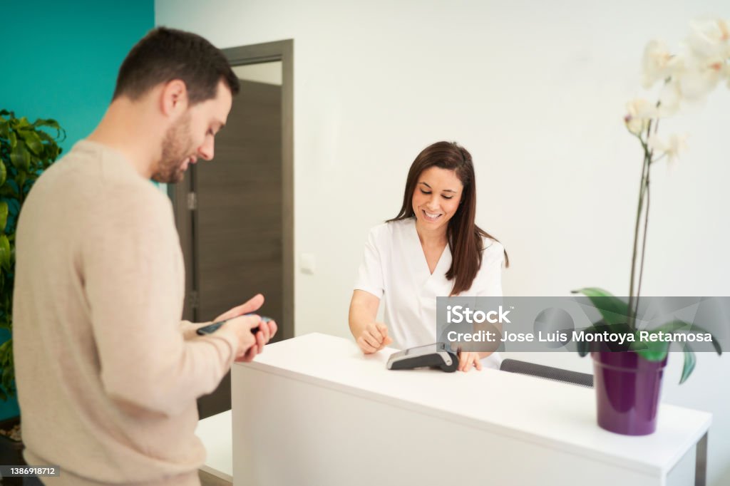a man paying for his physiotherapy treatment with his mobile phone Paying Stock Photo