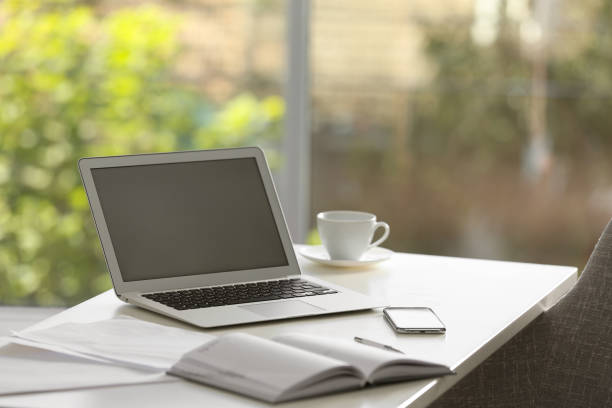 istock Modern laptop and supplies on table in office 1386920213