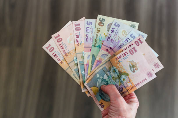 istock Hand holding stack of Romanian paper currency 1386922209