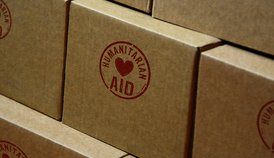 Humanitarian Aid stamp printed on cardboard box. Help refugees, volunteering and rescue during the crisis concept.