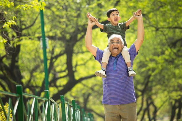 istock Old man carrying grandson on shoulders at park 1386923800