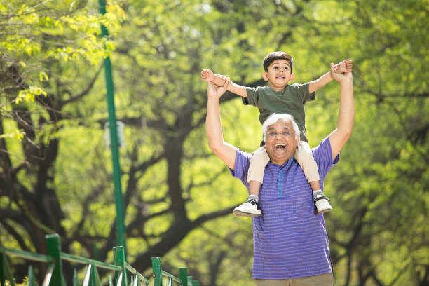 istock Old man carrying grandson on shoulders at park 1386923814
