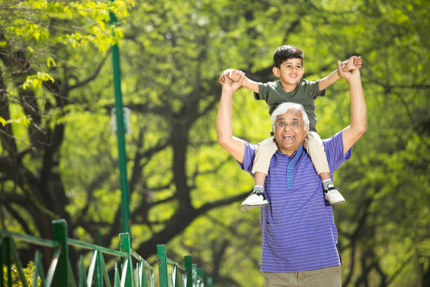istock Old man carrying grandson on shoulders at park 1386923835