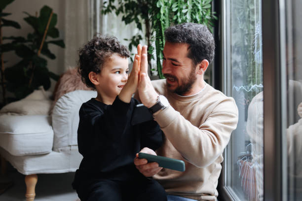 istock Happy Young Father And Son Playing Videogames On Smartphone Together 1386926082