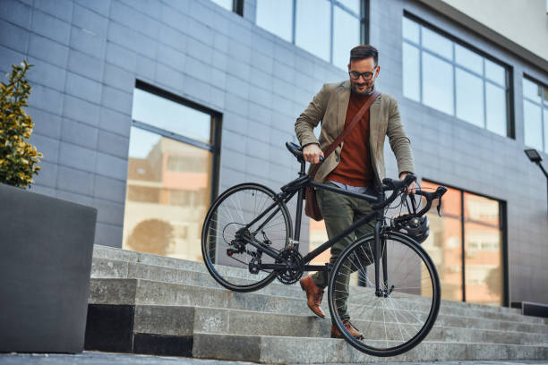 istock Handsome young businessman carrying bicycle down steps 1386927346