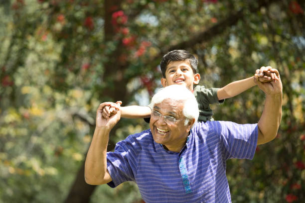 istock Old man carrying grandson on shoulders at park 1386928582