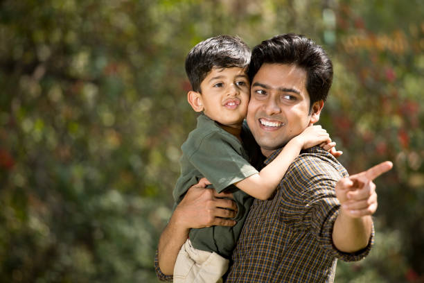 Cheerful father with cute little son admiring nature at park