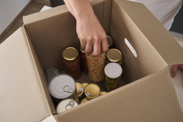 istock Unrecognizable man filling donation box with non-perishable food. 1386932235