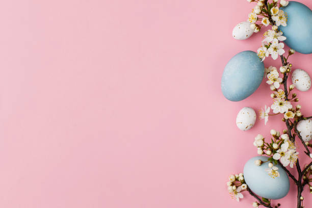 istock Stylish easter eggs and flowers flat lay on pink background. Modern natural dyed blue eggs and cherry blossom border. Greeting card template, easter background. Space for text. Happy Easter! 1386933104