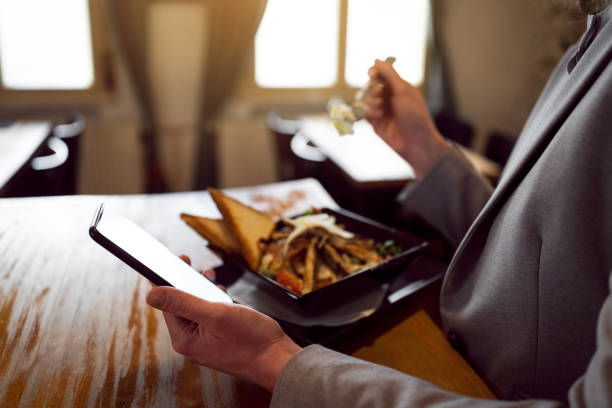 istock Unrecognizable businesswoman using mobile phone, while having a lunch in modern restaurant 1386933204