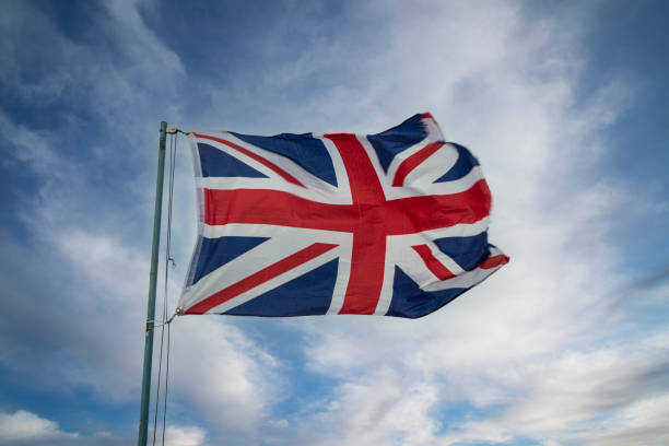 istock Union Jack Flag blowing in the wind against a blue sky. 1386933451