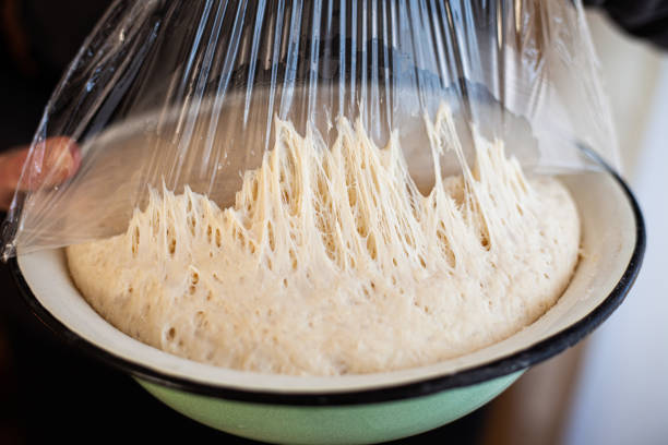 pasta per pizza fatta in casa in una ciotola. pane a lievitazione naturale. - impastare foto e immagini stock