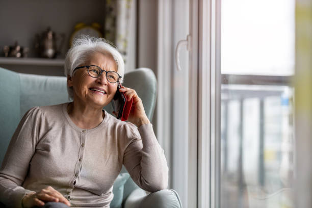 Senior woman using mobile phone at home stock photo