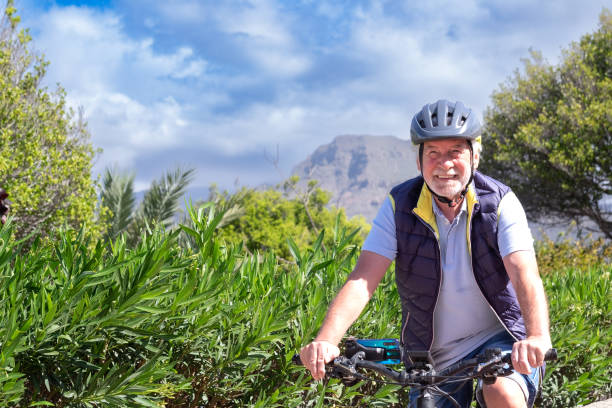 istock Happy active senior man with electro bikes standing outdoors in the park. Smiling elderly grandfather running in nature with his bicycle enjoying healthy lifestyle 1386939719